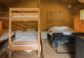 Interior de la tienda Safari La Rochette con literas y cama doble en Beter Uit Holiday Park Walsdorf, Luxemburgo.