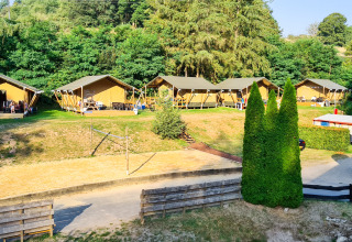 Tiendas de safari en Beter Uit Holiday Park Walsdorf, Luxemburgo, rodeadas de árboles y naturaleza verde.