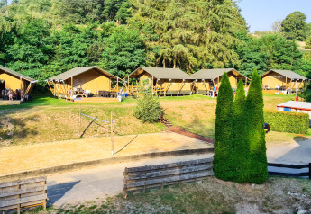 Tiendas de safari en Beter Uit Holiday Park Walsdorf, Luxemburgo, rodeadas de árboles y naturaleza verde.