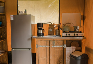 Cocina con nevera, cafetera y estufa en una tienda safari La Rochette en Walsdorf, parque de vacaciones.