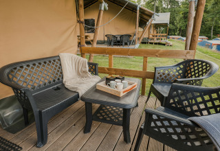 Zona de estar exterior con muebles de plástico en tarima de madera junto a tienda safari en Beter Uit Holiday Park Walsdorf.