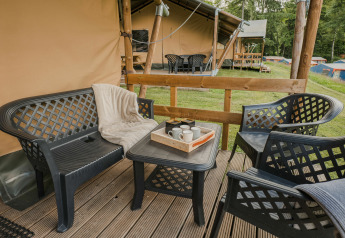 Zona de estar exterior con muebles de plástico en tarima de madera junto a tienda safari en Beter Uit Holiday Park Walsdorf.
