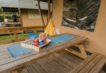 Mesa de picnic al aire libre con refrescos y aperitivos frente a una tienda safari en Beter Uit Holiday Park Walsdorf, Luxemburgo.