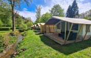 Tiendas tipo safari Lodge junto a un arroyo en Beter Uit Holiday Park Walsdorf, Luxemburgo, rodeadas de naturaleza.