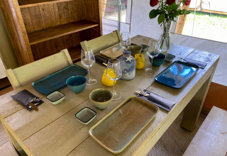Mesa puesta con platos coloridos y copas en una tienda lodge safari en Walsdorf, Luxemburgo, vacaciones.