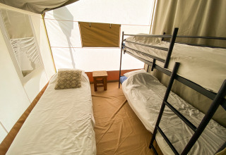 Interior de la tienda Lodge Eifel con litera, cama individual y mesa pequeña en Beter Uit Holiday Park Walsdorf.