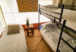 Interior de la tienda Lodge Eifel con cama individual y litera en Beter Uit Holiday Park Walsdorf, Luxemburgo.
