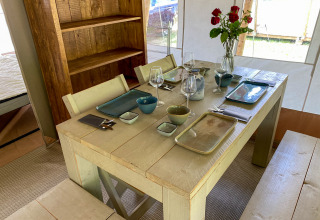 Mesa de comedor en la tienda Lodge Eifel de Beter Uit Holiday Park Walsdorf con vajilla y rosas rojas.