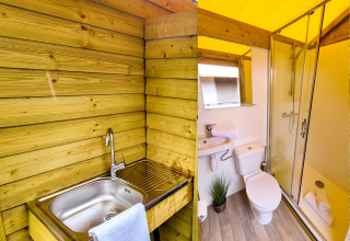 Baño con ducha, inodoro, lavabo y área de lavado exterior en una tienda safari en Beter Uit Walsdorf.