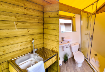 Baño con ducha, inodoro, lavabo y área de lavado exterior en una tienda safari en Beter Uit Walsdorf.
