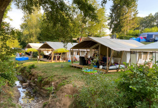 Tienda safari Lodge tent Eifel en Beter Uit Holiday Park Walsdorf, Luxemburgo, con huéspedes y entorno verde.