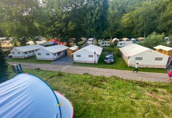 Vista de la tienda Lodge Eifel en Beter Uit Holiday Park Walsdorf, Luxemburgo, con tiendas y caravanas.