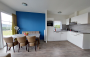 Moderne lodge met keuken, eettafel, lederen stoelen, een blauwe muur en veel natuurlijk licht.