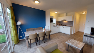 Moderne lodge-leefruimte met open keuken, blauwe accentwand, eettafel, stoelen en grote ramen.