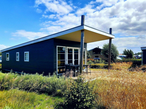 Komfort-Lodge im modernen Stil bei Kompas Camping - Westende, Belgien, umgeben von Natur und Himmel.