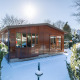 Veluwe lodge innevato al Bungalowpark Het Verscholen Dorp, Paesi Bassi, circondato da alberi invernali.