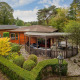 Lodge Veluwe au Bungalowpark Het Verscholen Dorp aux Pays-Bas, entourée de verdure et de beaux arbres.