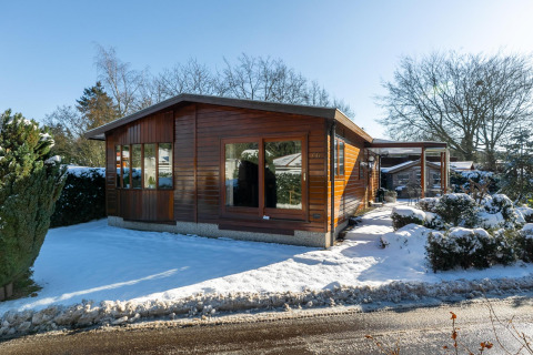 Veluwe lodge, een klein houten huisje in de sneeuw bij Bungalowpark Het Verscholen Dorp, Nederland, winter.