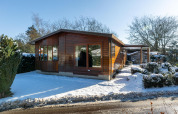 Veluwe Lodge, ein kleines Holzhaus im Schnee, im Bungalowpark Het Verscholen Dorp in den Niederlanden, Winterbild.