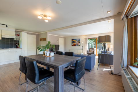 Lyst og moderne opholdsrum med spisebord, stue og udsigt til have i Veluwe Lodge, Het Verscholen Dorp.