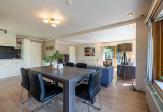 Lyst og moderne opholdsrum med spisebord, stue og udsigt til have i Veluwe Lodge, Het Verscholen Dorp.