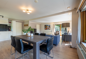 Sala luminosa y moderna con comedor, sala de estar y vista al jardín en Veluwe Lodge, Het Verscholen Dorp.