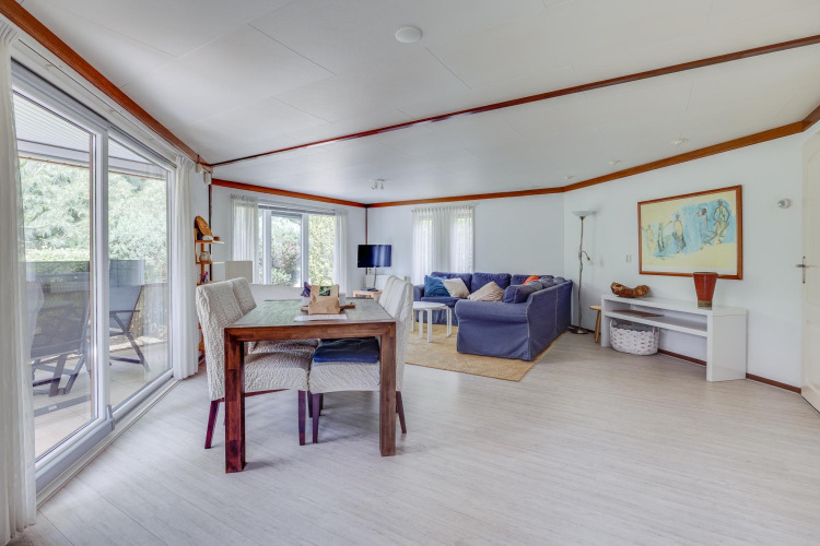 Helles Wohnzimmer mit Esstisch, Sofa und großen Fenstern in der Veluwe Lodge, Het Verscholen Dorp.