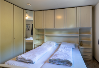 Slaapkamer in de Veluwe Lodge bij Bungalowpark Het Verscholen Dorp in Nederland met twee bedden en kasten.