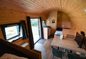 Interieur van de houten Woodlodge bij Camping de Noetselerberg in Nederland met zicht op tafel en bed.
