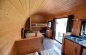 Houten interieur van een knusse lodge bij Camping de Noetselerberg met stapelbedden en kitchenette.