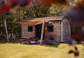 Woodlodge met picknicktafel en zitje buiten bij Camping de Noetselerberg in Nederland, midden in het groen.