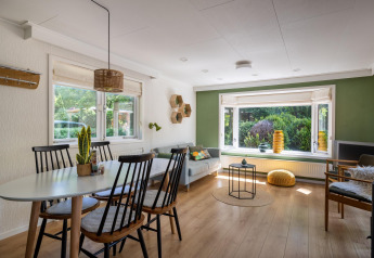 Salon lumineux et moderne à Heide lodge dans Bungalowpark Het Verscholen Dorp aux Pays-Bas avec grandes fenêtres.