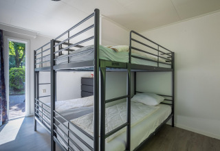 Zimmer mit Etagenbetten und hellem Interieur in der Heide Lodge im Bungalowpark Het Verscholen Dorp, Niederlande.