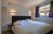 Schlafzimmer in der Heide Lodge im Bungalowpark Het Verscholen Dorp in den Niederlanden mit Doppelbett.