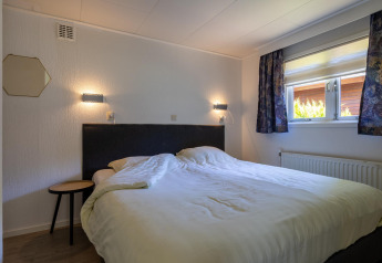 Camera da letto nella Heide Lodge al Bungalowpark Het Verscholen Dorp, Paesi Bassi, con letto matrimoniale.