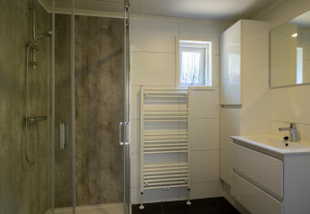 Modern bathroom with shower, sink, mirror, and towel radiator at Heide lodge in Het Verscholen Dorp, Netherlands.