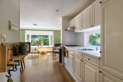 Vue intérieure de la Heide lodge au Bungalowpark Het Verscholen Dorp, montrant cuisine et salon.