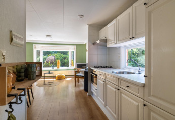 Vue intérieure de la Heide lodge au Bungalowpark Het Verscholen Dorp, montrant cuisine et salon.