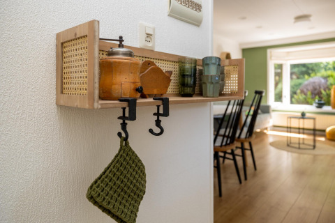 Estante de pared con utensilios de cocina y paño verde en interior luminoso del Heide lodge, Países Bajos.