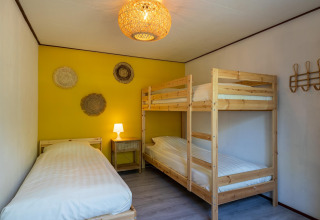 Dormitorio en Heide lodge en Bungalowpark Het Verscholen Dorp, Países Bajos, con cama individual y litera.