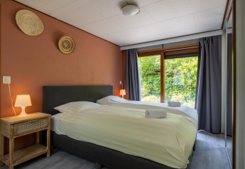 Dormitorio moderno en Heide lodge, Het Verscholen Dorp, con dos camas y ventana con vistas al jardín.