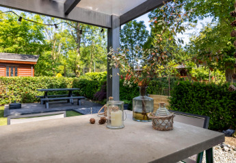 Terrasse ved Heide lodge i Bungalowpark Het Verscholen Dorp, Holland, med borddekoration og grøn udsigt.