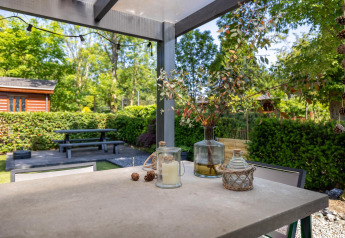Patio table at Heide lodge, Bungalowpark Het Verscholen Dorp in the Netherlands, surrounded by lush greenery.