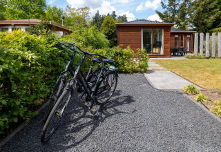 Bicycles parked on a gravel path in front of Heide lodge at Bungalowpark Het Verscholen Dorp, Netherlands.