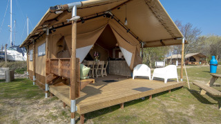 Tienda safari con terraza de madera en Marina Parcs Almere, Países Bajos, rodeada de barcos y naturaleza