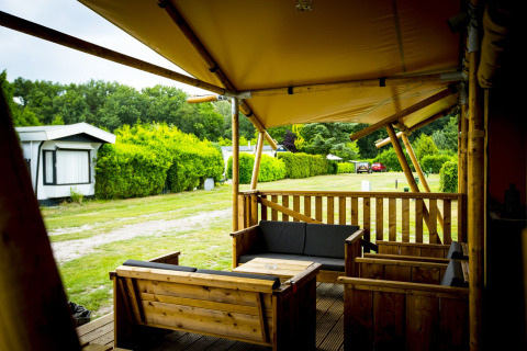 Terraza de madera con muebles lounge de una tienda safari Glamping Lodge en Holiday Park Duinhoeve, Países Bajos.