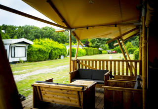 Houten terras met loungezetels bij safaritent Glamping Lodge in Holiday Park Duinhoeve, Nederland.