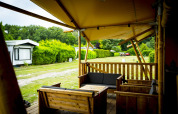 Houten terras met loungebanken bij safaritent Glamping Lodge op vakantiepark Duinhoeve, Nederland.