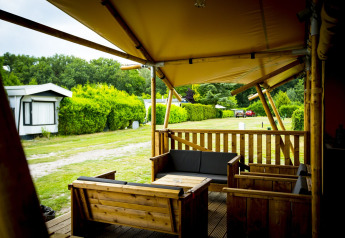 Terrazza in legno con mobili lounge vicino a tenda safari Glamping Lodge a Holiday Park Duinhoeve, Paesi Bassi.