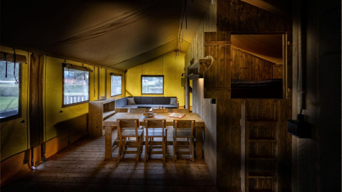 Interior de una tienda de safari Glamping Lodge con muebles de madera en Holiday Park Duinhoeve, Países Bajos.